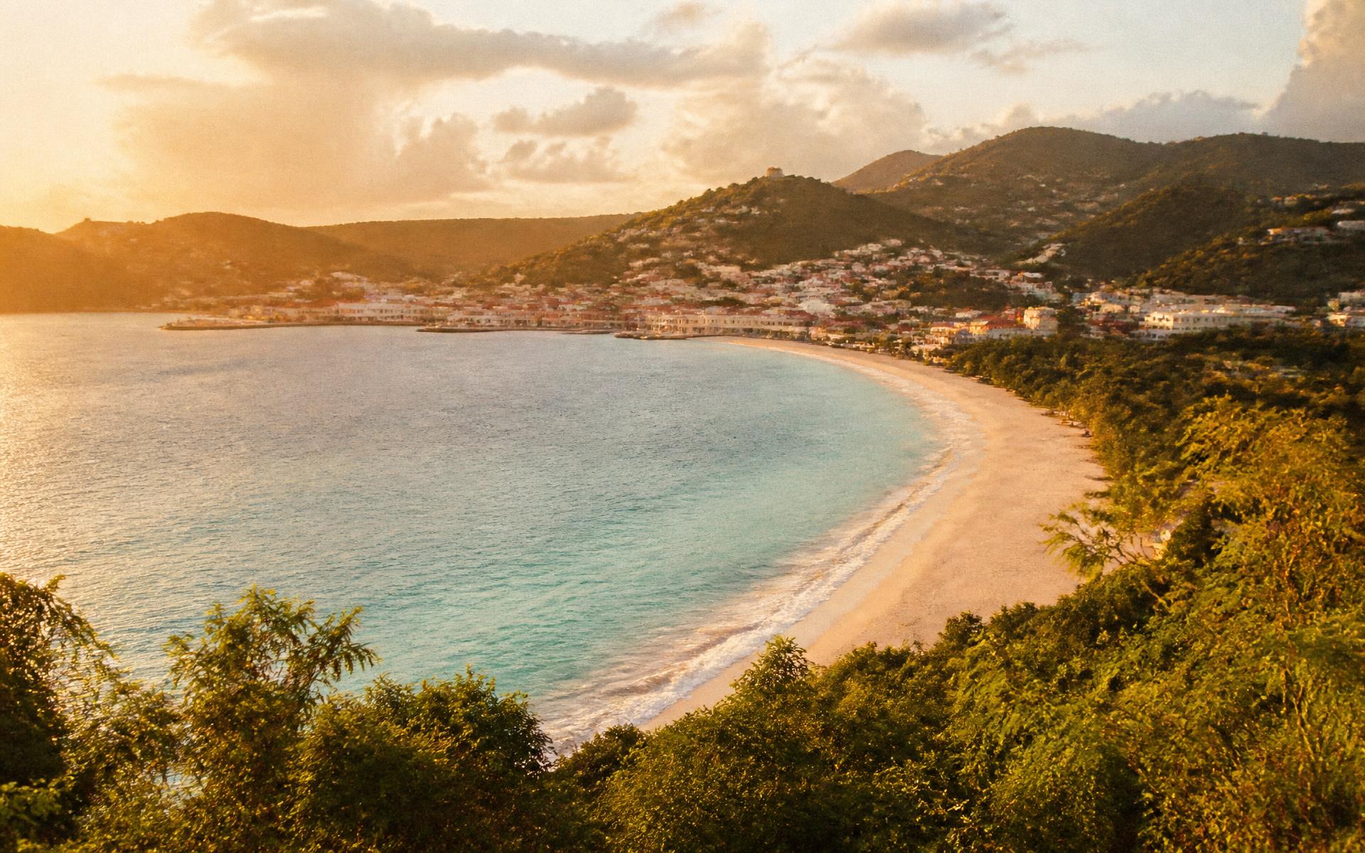 Grand Anse beach in Grenada at golden hour, with St. George's on the hillside beyond